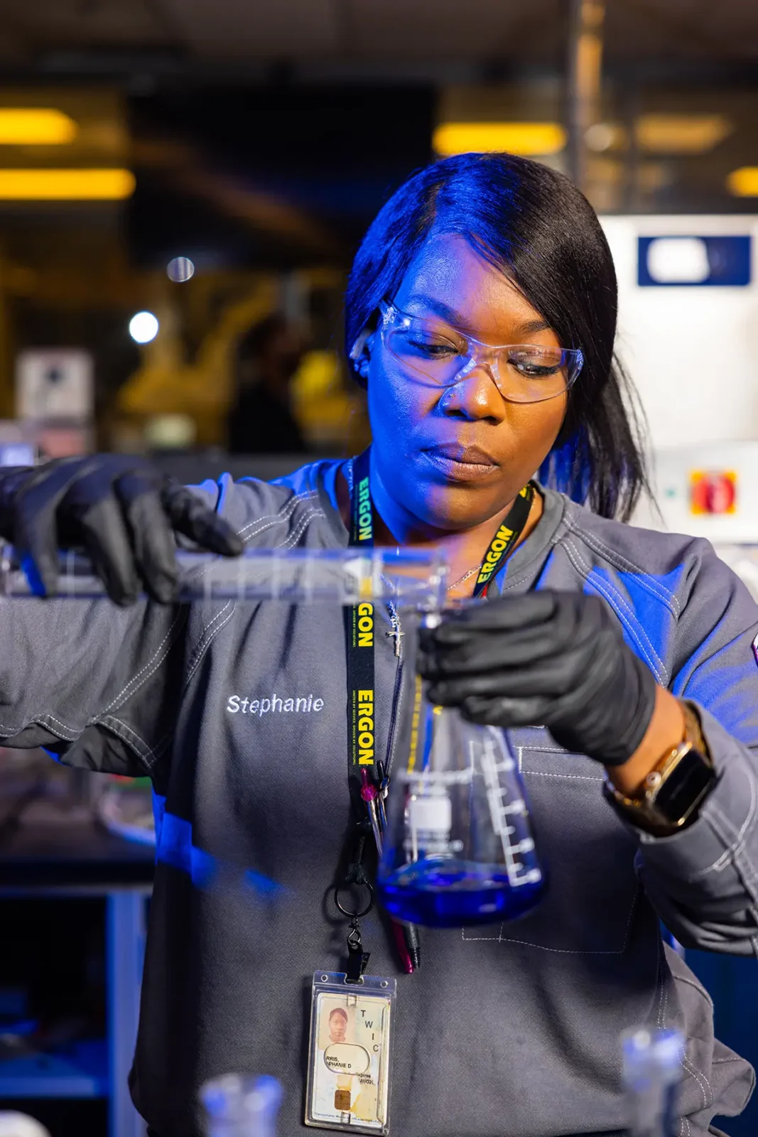 Woman pours blue liquid into flask
